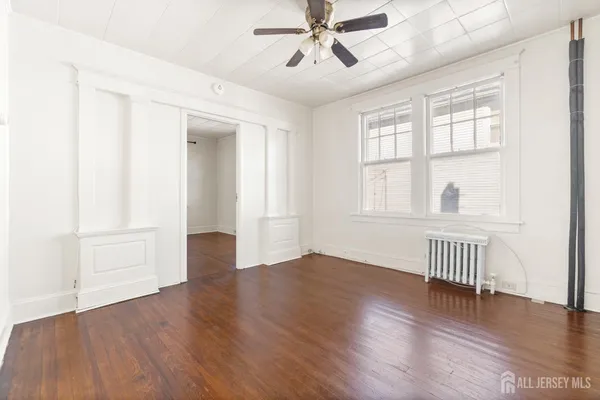 an empty room with wooden floor fan and windows