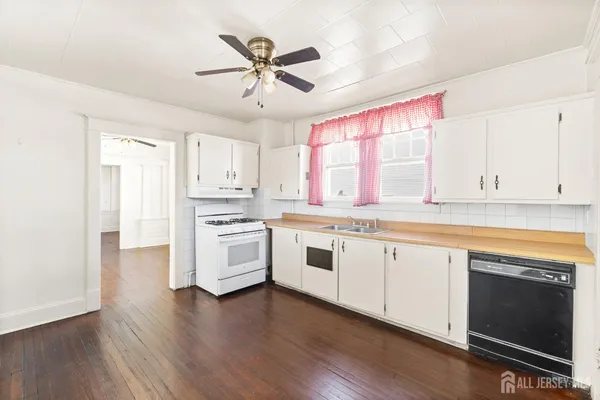 a kitchen with a stove a sink and white cabinets