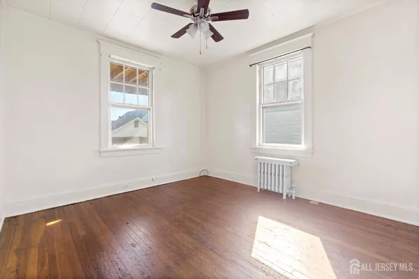 an empty room with wooden floor chandelier and windows