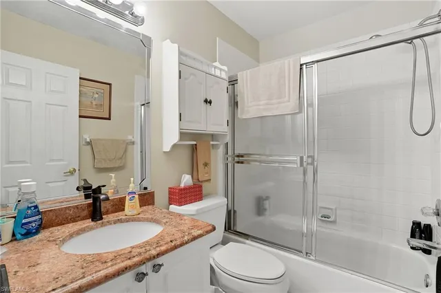 a bathroom with a granite countertop shower sink vanity mirror and toilet