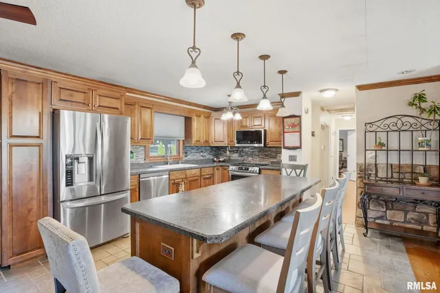a kitchen with stainless steel appliances a dining table chairs and stove top oven