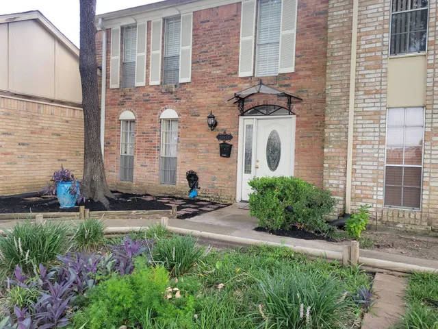 a view of a brick house with a yard and plants