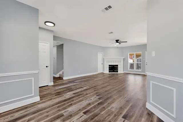 an empty room with wooden floor fireplace and windows