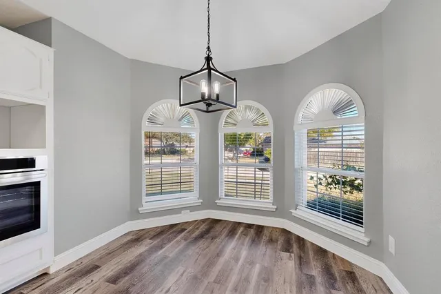 a view of an empty room with wooden floor fireplace and a window