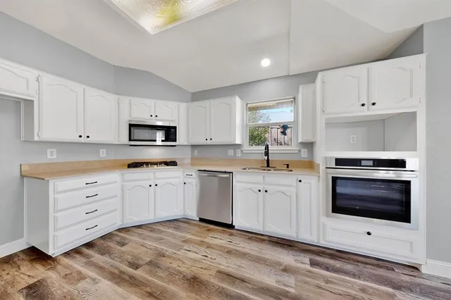 a kitchen with cabinets stainless steel appliances and sink