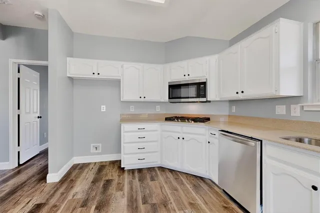 a kitchen with granite countertop white cabinets and stainless steel appliances
