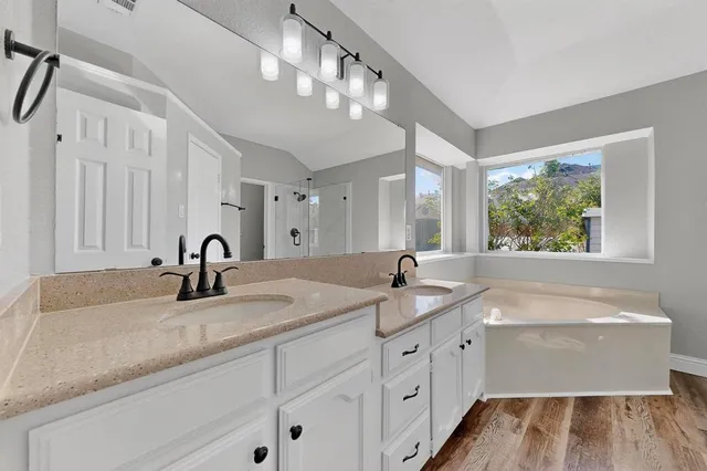 a bathroom with a granite countertop double vanity sink a window and a mirror