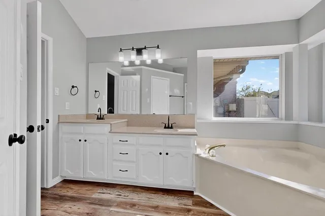 a spacious bathroom with a tub sink and mirror