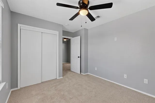an empty room with ceiling fan and window