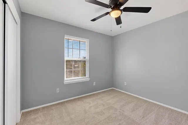 an empty room with chandelier fan and windows