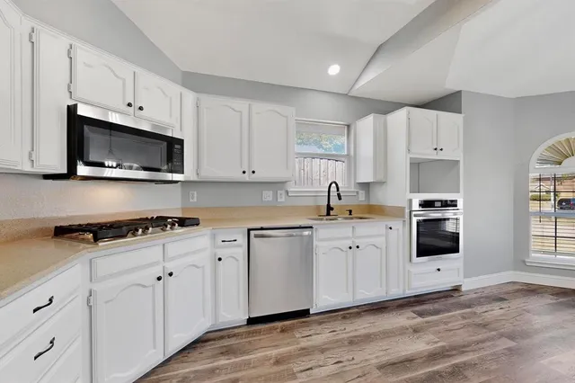 a kitchen with stainless steel appliances granite countertop a stove a sink and a microwave