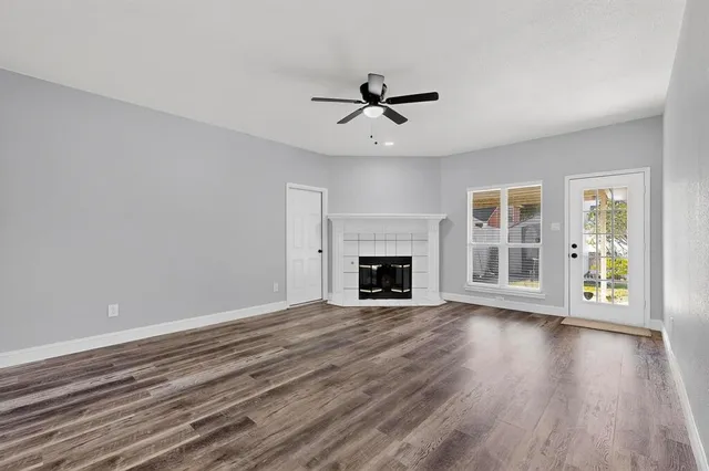 a view of an empty room with wooden floor fireplace and a window