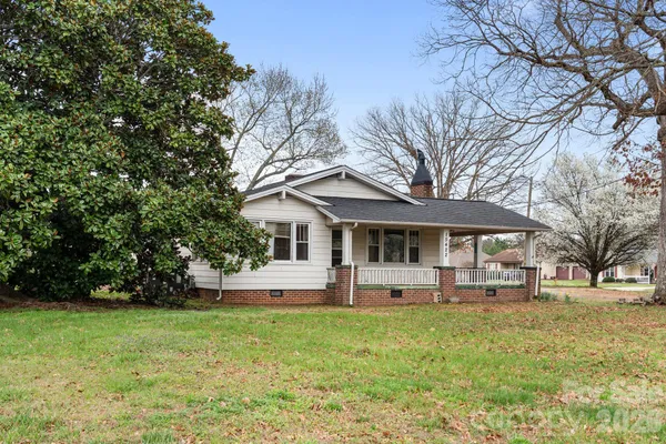 a front view of a house with a garden and trees