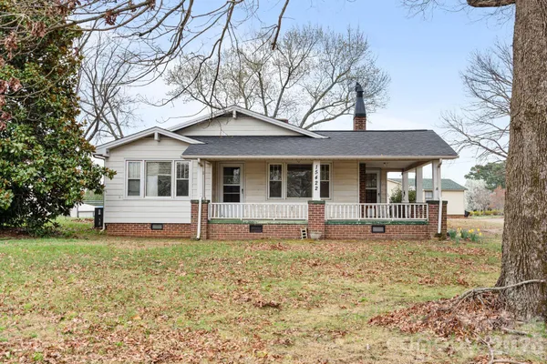 a view of an empty room with wooden floor fireplace and a window