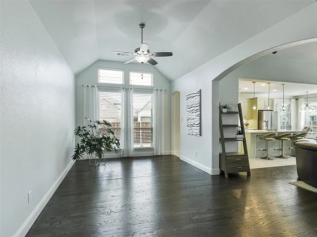 a view of an empty room with wooden floor and a chandelier