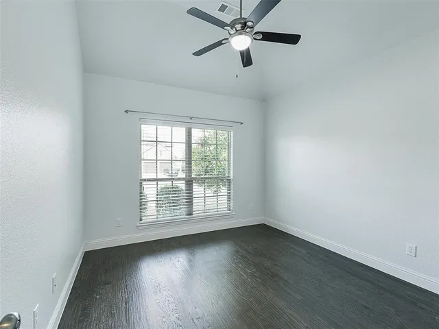 an empty room with wooden floor fan and windows