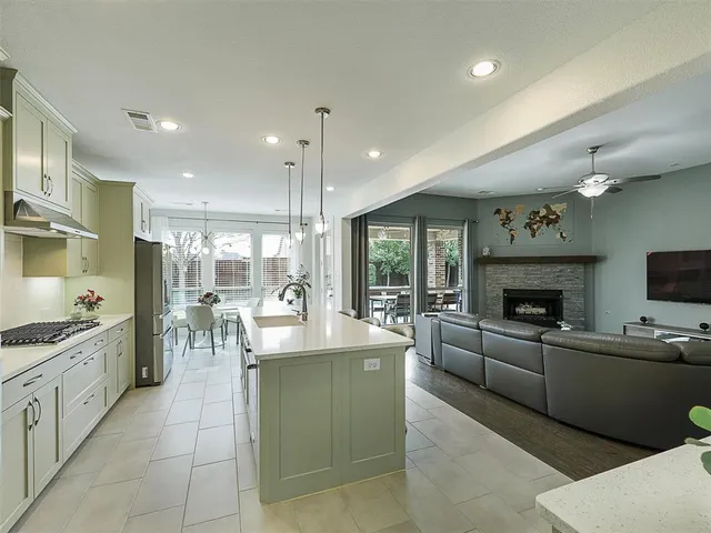 a large living room with stainless steel appliances granite countertop couches a fireplace a flat screen tv and a view of kitchen