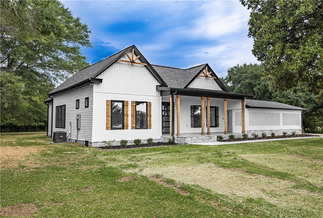 2817 Broadway Lake Road Anderson, SC 29621 - Photo 4 of 41 A striking modern farmhouse with gabled roofs and a welcoming columned porch stands amidst verdant surroundings.