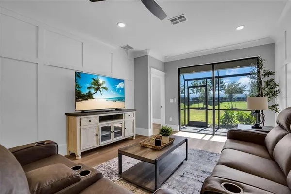 a living room with furniture a flat screen tv and a floor to ceiling window