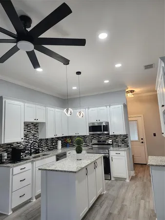 a kitchen with stainless steel appliances kitchen island granite countertop a stove a sink and a refrigerator