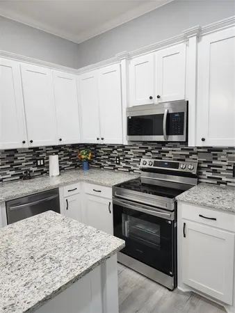 a kitchen with granite countertop white cabinets and stainless steel appliances