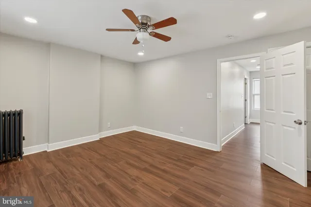 an empty room with wooden floor and a ceiling fan