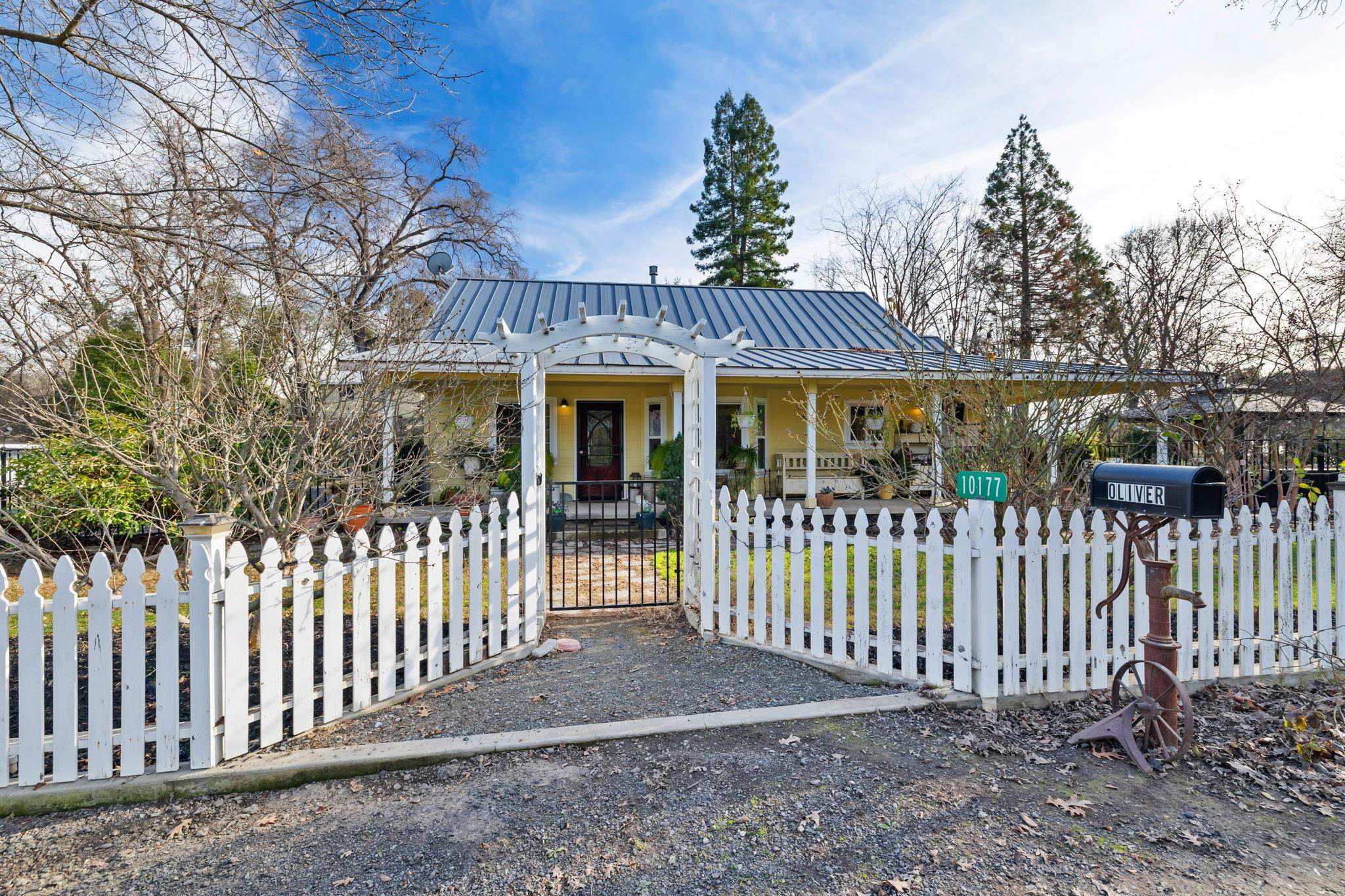 View of front of home with a fenced front yard, a metal roof, a gate, and a porch