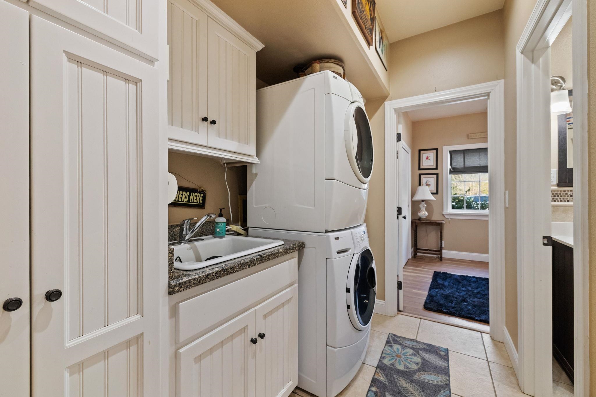 10177 Pulpit Rock Road Jamestown, CA 95327 - Photo 22 of 60 Laundry area with stacked washer / drying machine, light tile patterned flooring, and cabinet space