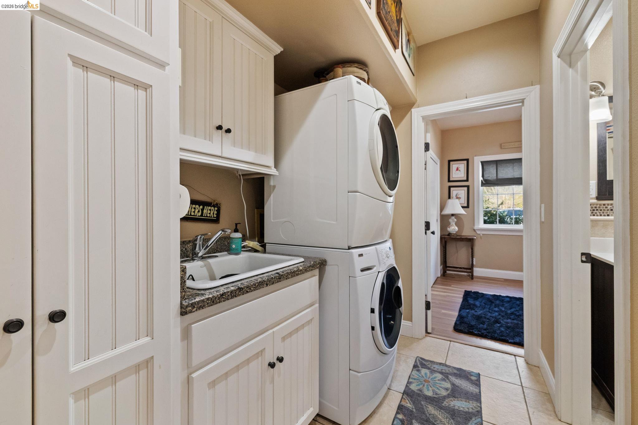 10177 Pulpit Rock Road Jamestown, CA 95327 - Photo 23 of 60 Laundry area with stacked washer / drying machine, light tile patterned flooring, and cabinet space