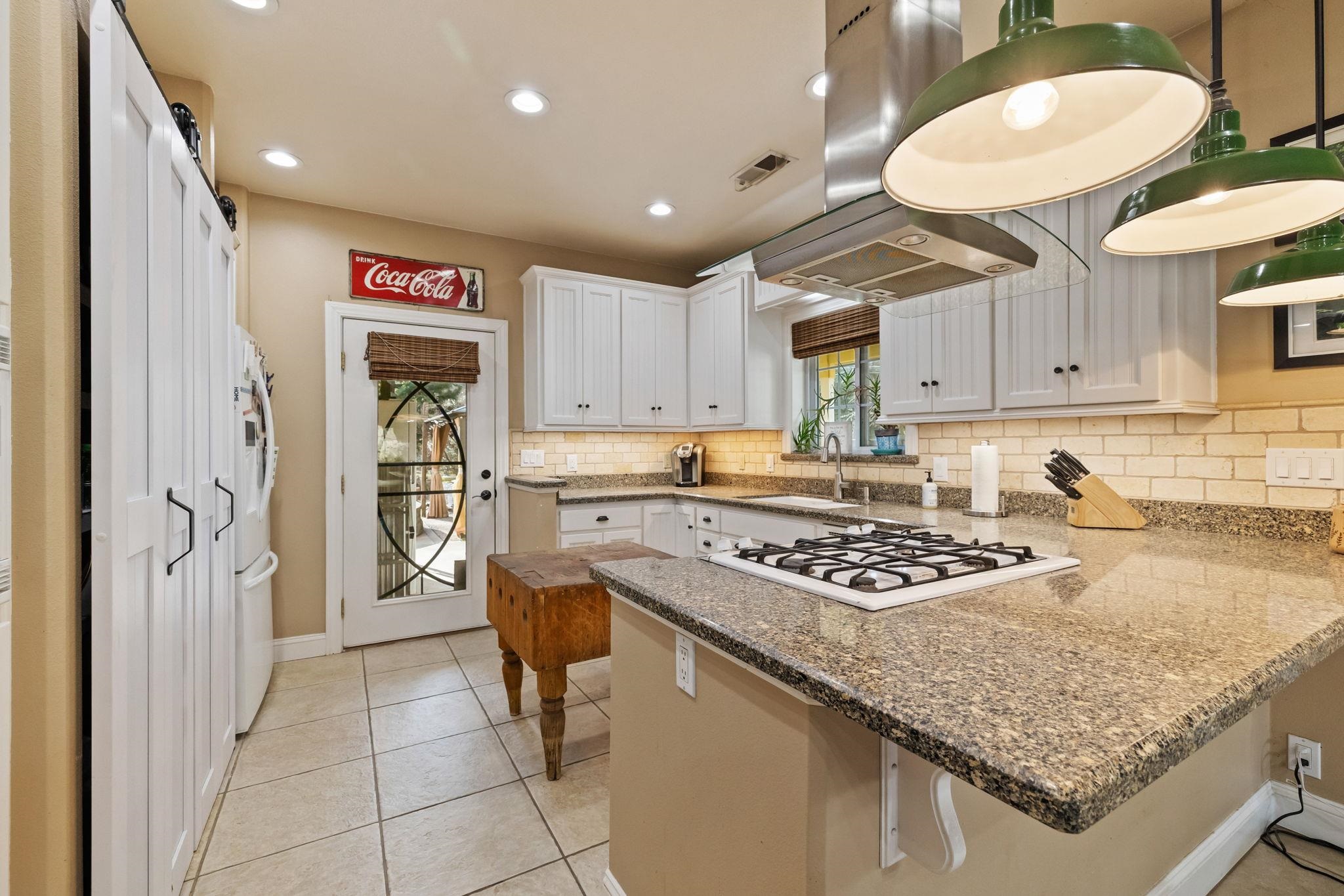 10177 Pulpit Rock Road Jamestown, CA 95327 - Photo 9 of 60 Kitchen featuring a peninsula, white cabinets, a breakfast bar, decorative backsplash, and exhaust hood
