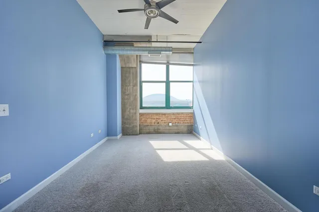 an empty room with a ceiling fan and window