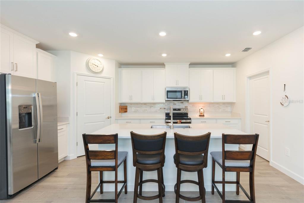 10806 Gable Dig Loop San Antonio, FL 33576 - Photo 17 of 73 a kitchen with stainless steel appliances a dining table chairs and refrigerator