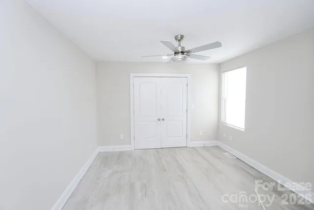 an empty room with a window and a fan