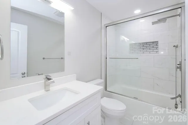 a bathroom with a shower sink vanity mirror and toilet