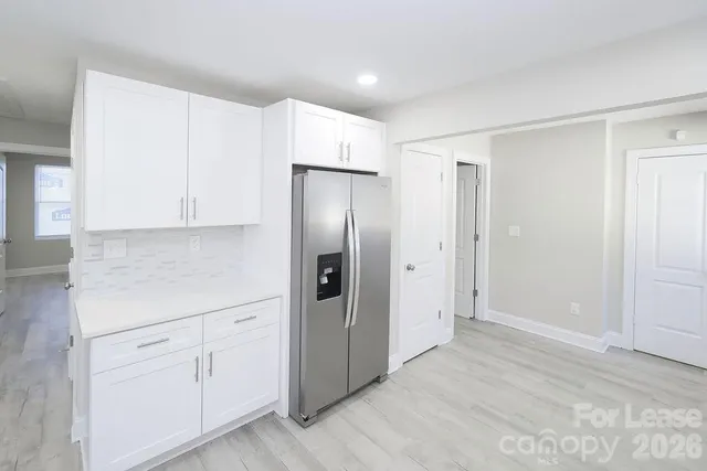 a view of a kitchen with white cabinets and wooden floor