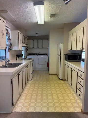 a kitchen with white cabinets a sink stove and refrigerator