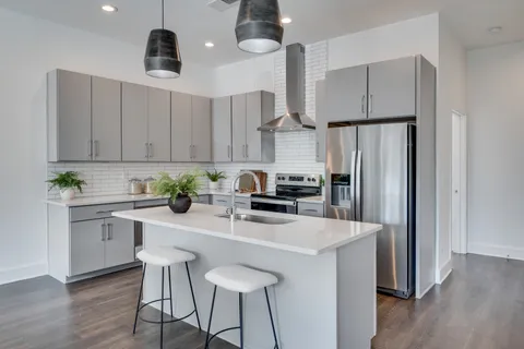 a kitchen with stainless steel appliances a dining table chairs sink refrigerator and cabinets