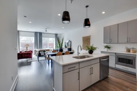 a kitchen with stainless steel appliances granite countertop a sink dishwasher a stove and a dining table with wooden floor