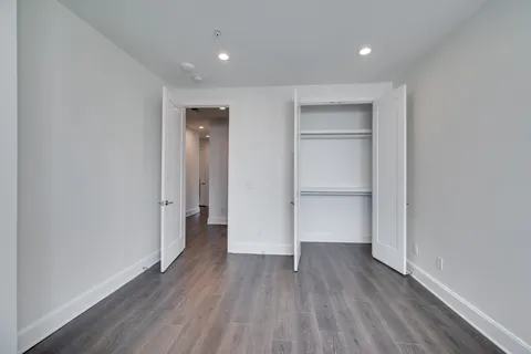 a view of an empty room with wooden floor and closet