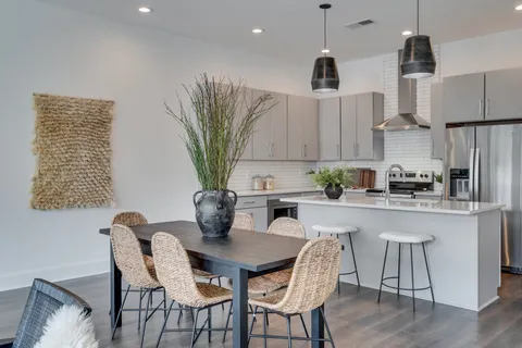 a kitchen with stainless steel appliances a dining table chairs and a refrigerator
