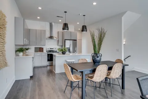 a kitchen with stainless steel appliances a dining table chairs and a refrigerator