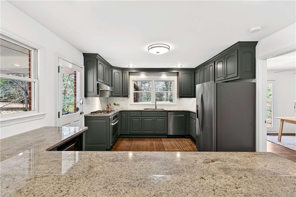 632 Willivee Drive Decatur, GA 30033 - Photo 12 of 44 a kitchen with stainless steel appliances kitchen island granite countertop a refrigerator a sink dishwasher and wooden cabinets with wooden floor