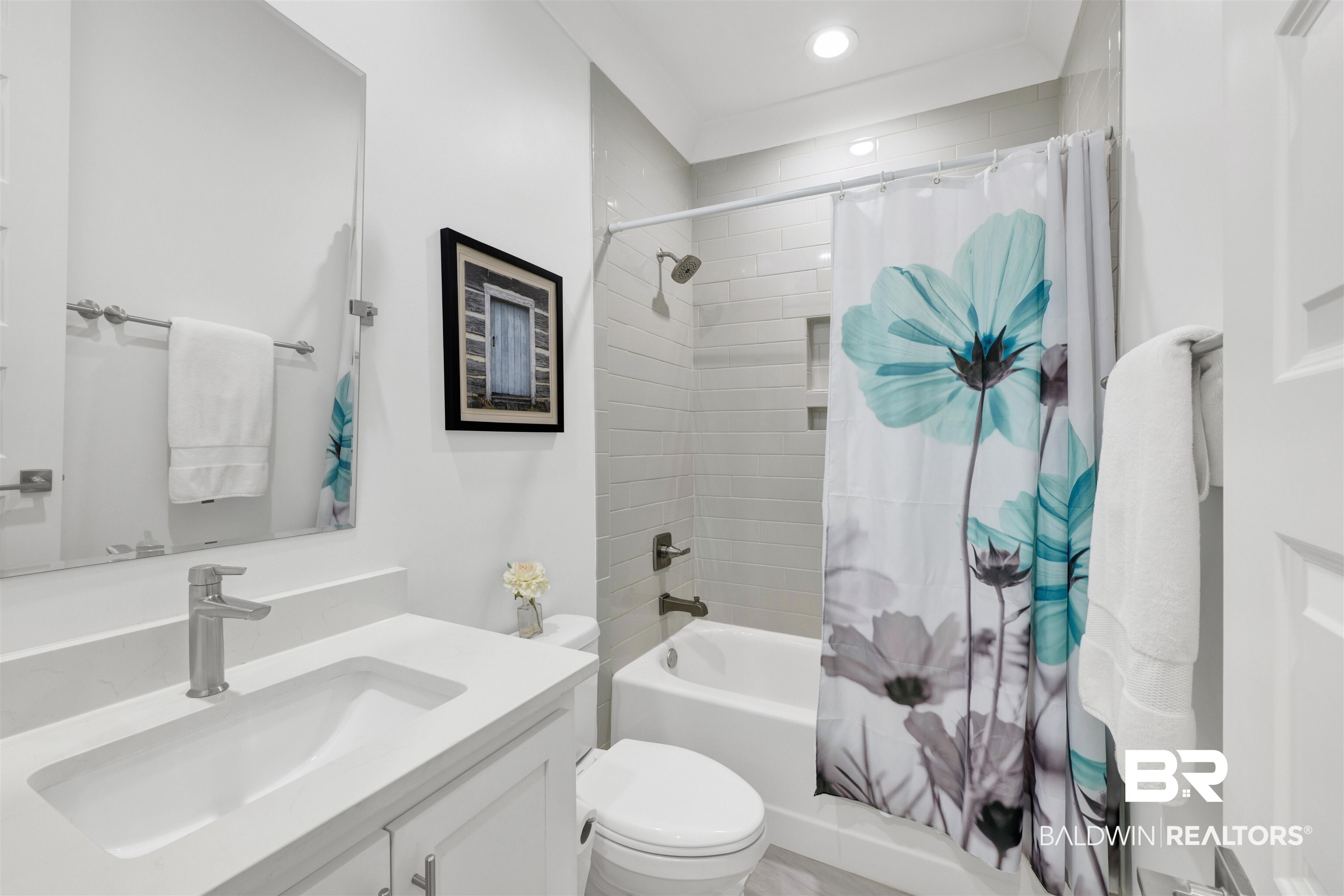 21702 Pillars Street Fairhope, AL 36532 - Photo 31 of 54 Bathroom featuring a white vanity with an integrated sink and brushed nickel faucet, a frameless wall mirror, and a tub-shower combination with horizontal tile surround and recessed shelving