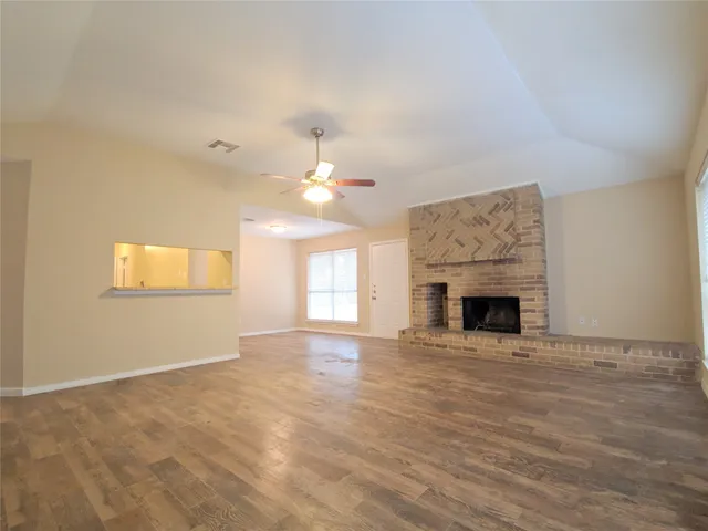 an empty room with fireplace fan and windows