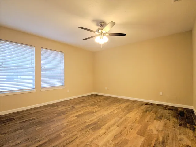 a view of an empty room with window and wooden floor
