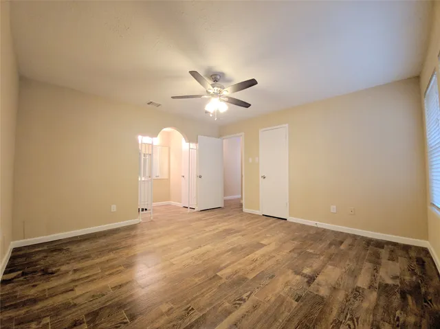 a view of an empty room with chandelier fan and window