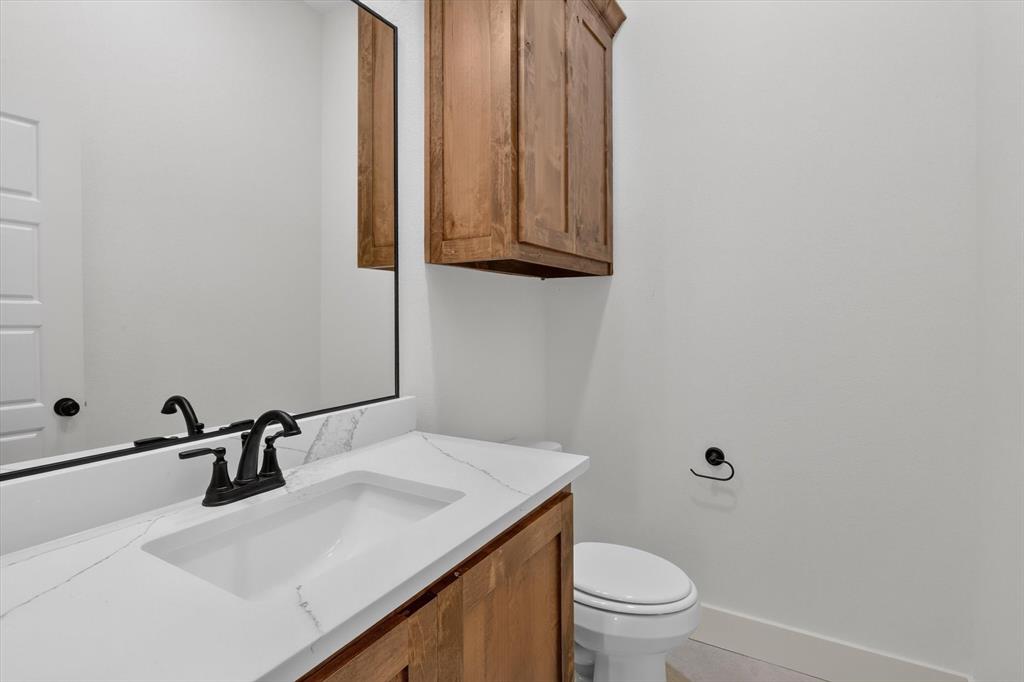 471 Red Bird Drive Springtown, TX 76082 - Photo 29 of 35 White vanity with an integrated rectangular sink, stone-finish countertop, matte black faucet, and coordinating hardware