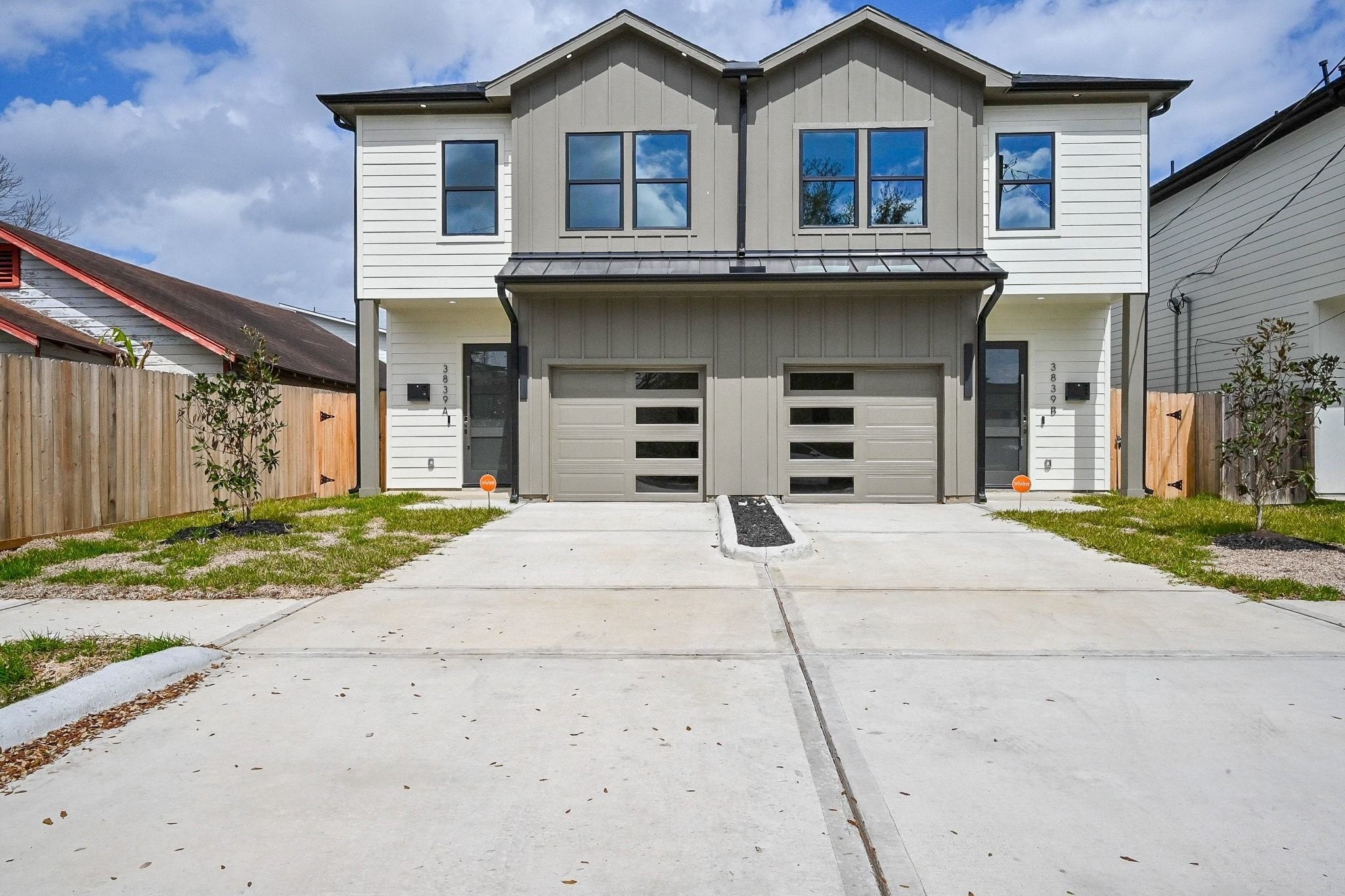 This modern duplex features a clean, contemporary design with a dual-garage and a spacious driveway. The exterior combines neutral tones with sleek lines, offering a stylish and low-maintenance facade. Perfect for those seeking a modern living space.