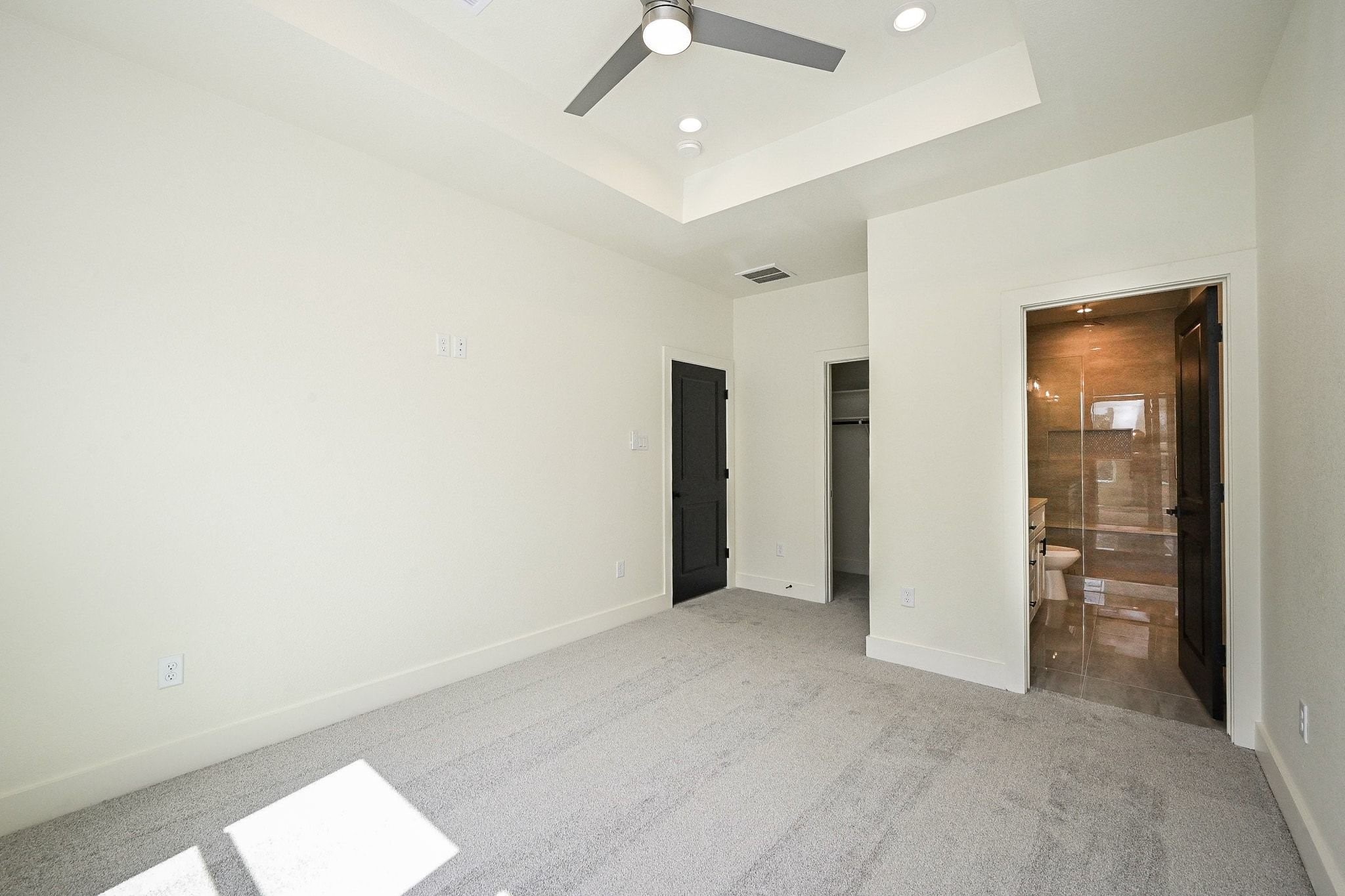 3839 Noah Street, Unit B Houston, TX 77021 - Photo 11 of 19 This is a bright bedroom featuring a neutral color scheme with carpeted flooring. It includes a ceiling fan, recessed lighting, and an ensuite bathroom with modern fixtures. The room also has a walk-in closet, providing ample storage space.