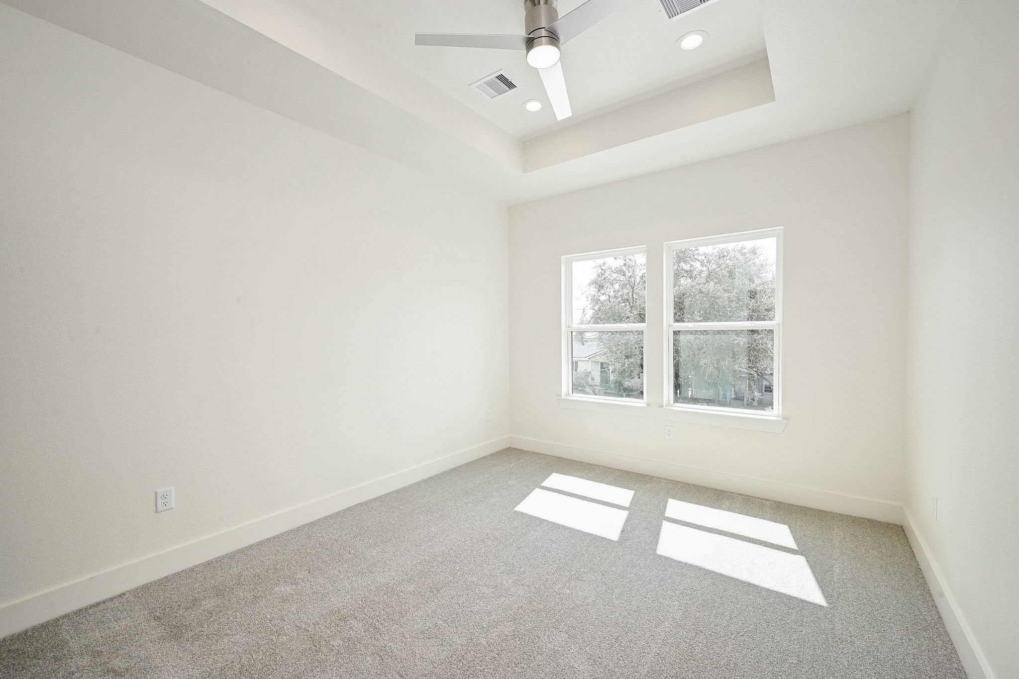 3839 Noah Street, Unit B Houston, TX 77021 - Photo 9 of 19 Bright, spacious room with large windows, neutral walls, and carpeted flooring. Features a modern ceiling fan and recessed lighting, offering a clean and comfortable space.